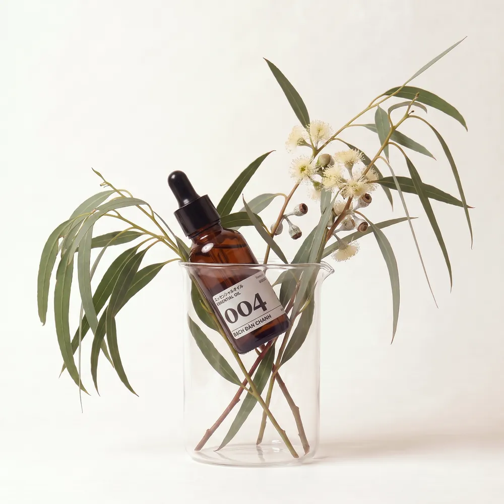 Tinh dầu Bạch Đàn Chanh – Lemon Eucalyptus · chai tinh dầu trong ly nguyên liệu | Lê Mai