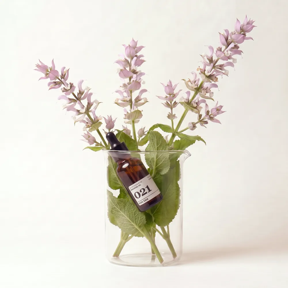 Tinh dầu Đơn Sâm – Clary Sage · chai tinh dầu trong ly nguyên liệu | Lê Mai