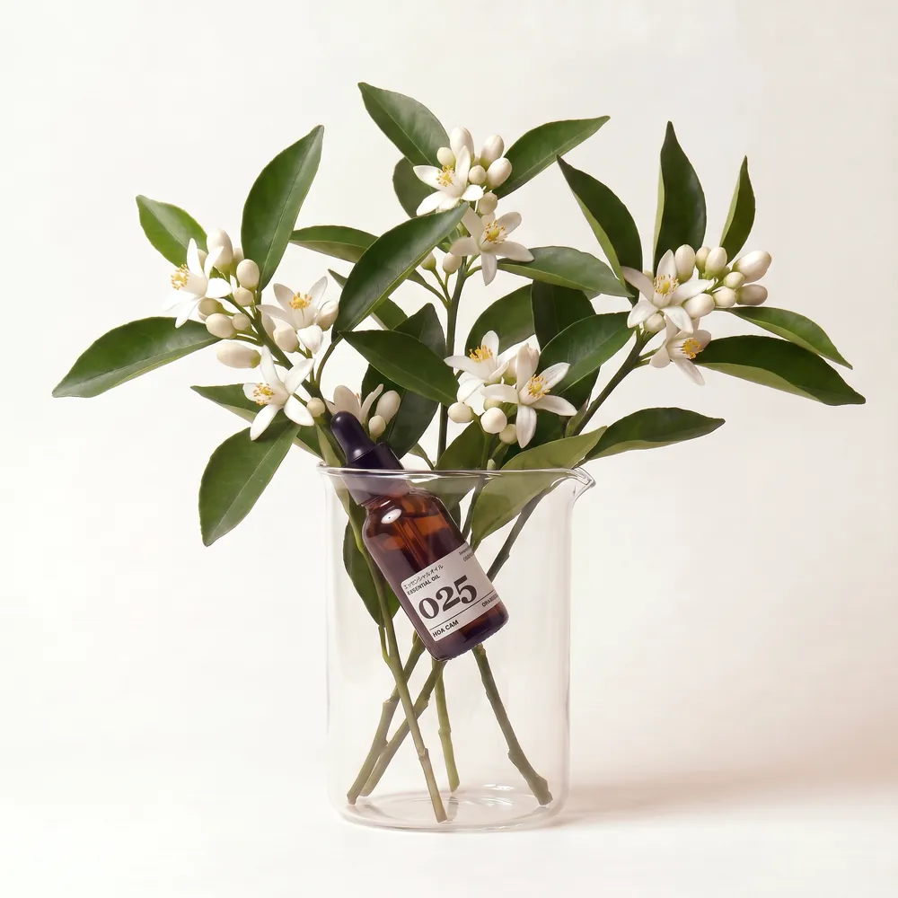 Tinh dầu Hoa Cam – Orange Blossom · chai tinh dầu trong ly nguyên liệu | Lê Mai