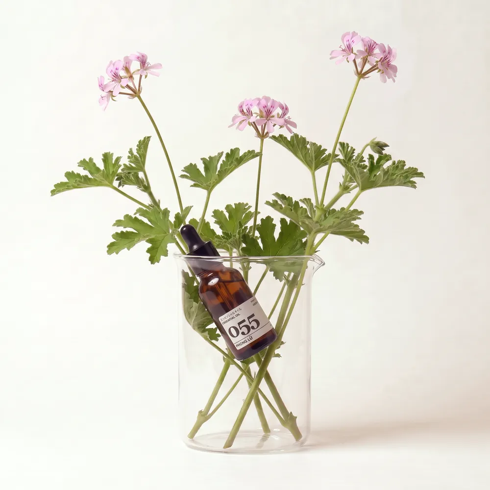 Tinh dầu Phong Lữ – Geranium · chai tinh dầu trong ly nguyên liệu | Lê Mai