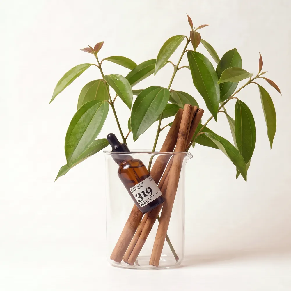 Tinh dầu Quế Ceylon – Ceylon Cassia · chai tinh dầu trong ly nguyên liệu | Lê Mai
